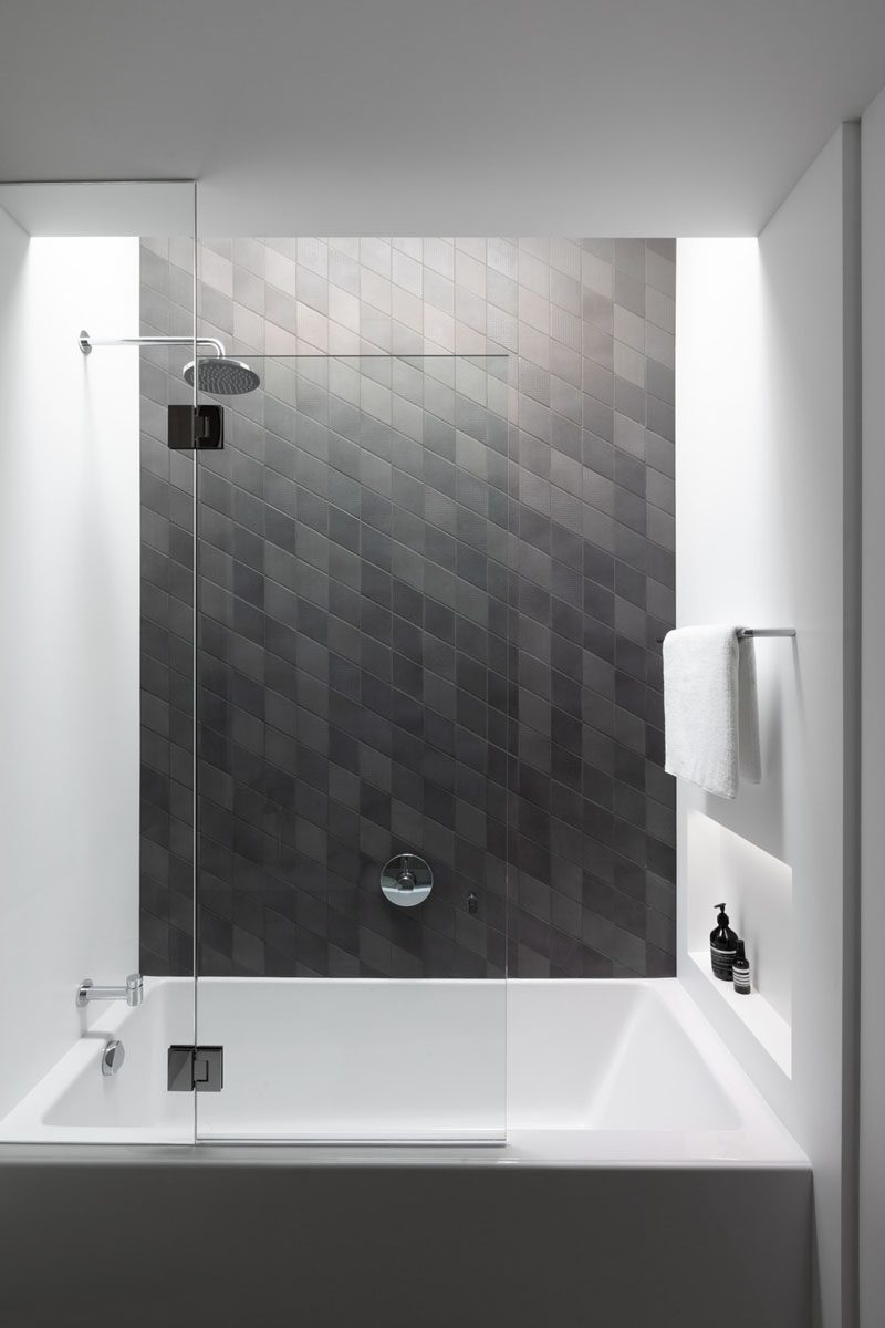 This modern grey bathroom features a shower niche that can be accessed from the shower and the bath. #ShowerNicheIdeas #ShowerNiche #ModernBathroom #BathroomDesign #BathroomIdeas