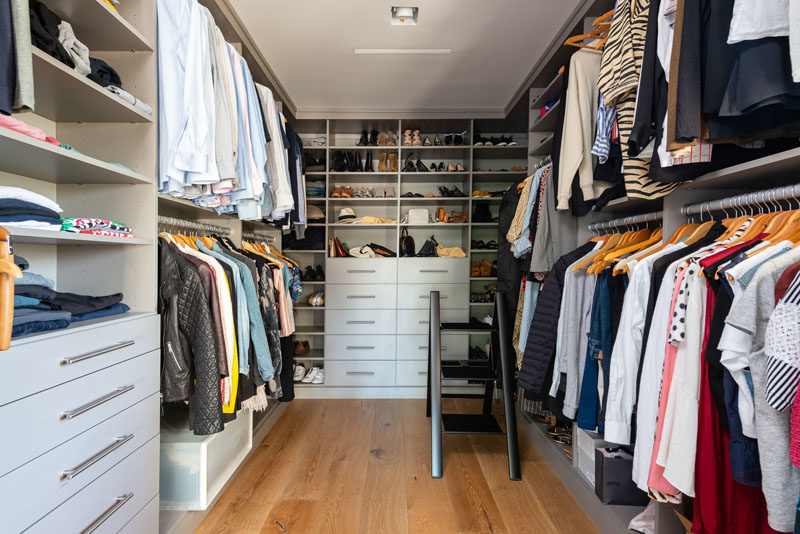 This modern walk-in closet has shelving, drawers, and plenty of space to hang clothes. #ModernWalkInCloset #WalkInCloset #Storage
