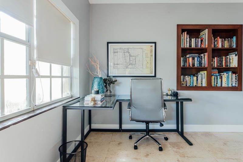 This modern guest bedroom has a workstation with a steel and glass corner desk and a built-in Bookshelf. #HomeOffice #Bookshelf