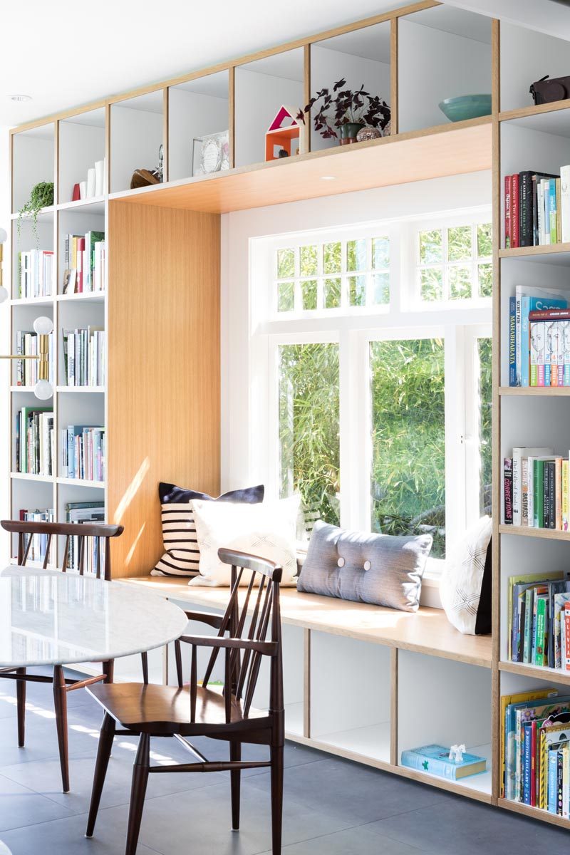 This modern house has a wood framed built-in window seat that's surrounded by open shelving, creating places to store books, decorative items, and toys. #WindowSeat #Shelving #InteriorDesign #DiningRoom