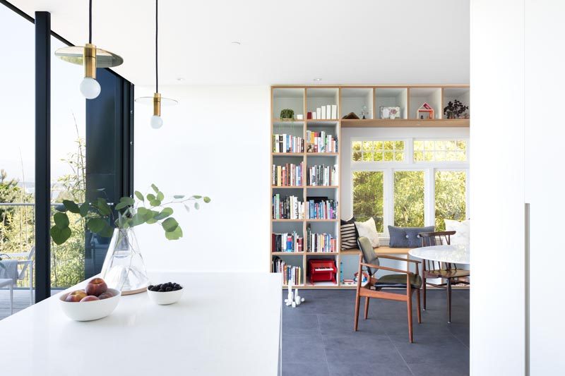 This modern house has a wood framed built-in window seat that's surrounded by open shelving, creating places to store books, decorative items, and toys. #WindowSeat #Shelving #InteriorDesign #DiningRoom