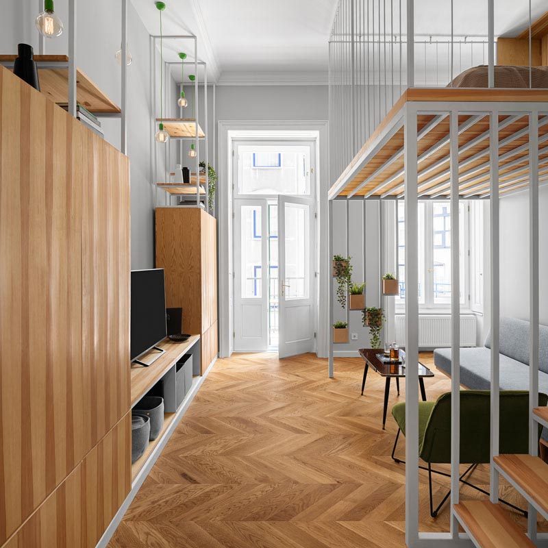 In this living room, wood cabinets provide storage and a place to display the television, while doors open to a small balcony. #LivingRoom #Storage #InteriorDesign