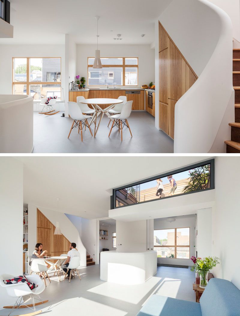 This modern house has an open plan interior with a dining area that's adjacent to a u-shaped kitchen. Custom-built wood cabinets have been built into the wall. #DiningRoom #Kitchen #WoodCabinets