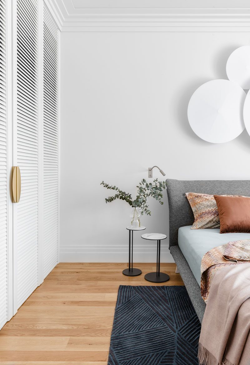 In this modern bedroom, white closets match the white walls, while the wood flooring has a natural honey hue. #ModernBedroom #BedroomDesign #WoodFlooring