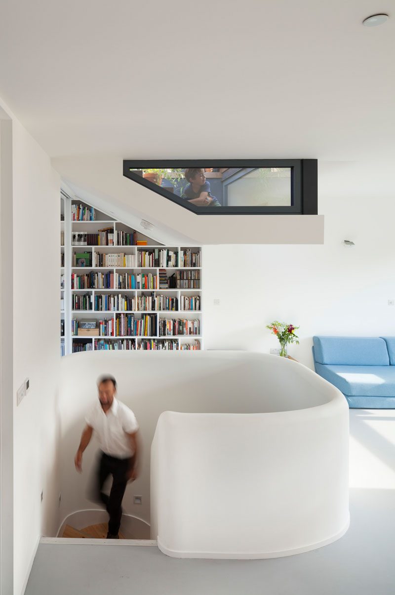 This modern house has a window and a bookshelf that follow the angle of the wall.