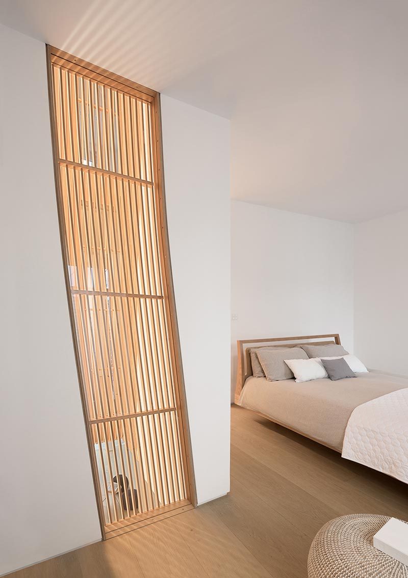 This modern and minimalist bedroom features a wood slat accent that allows light from the other side to pass through. #WoodSlats #ModernBedroom