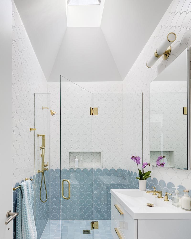 The design of this modern bathroom includes an vaulted ceiling that guides the eye up to the skylight, making the space feel large and open. #ModernBathroom #BathroomDesign #BathroomSkylight #VaultedCeiling