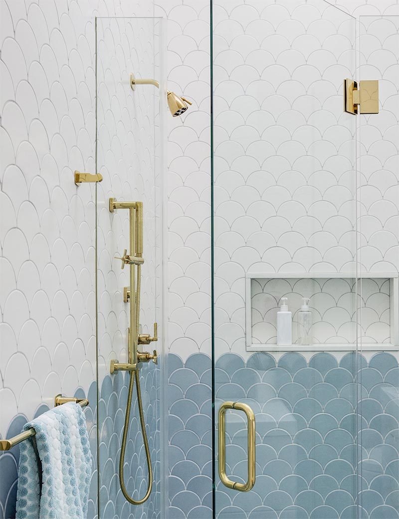 This modern bathroom has gold hardware found through the bathroom, like the towel holder, the supports that hold the glass shower screen in place, the shower head, taps, and hand-held shower. #ModernBathroom #BathroomDesign #GoldBathroomHardware