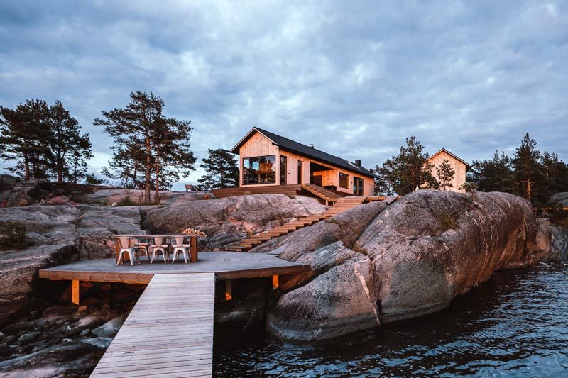 Steps lead from this modern holiday house down to a deck that's nestled between the rocks, and attaches to a small jetty. #Landscaping #Deck #ModernCabin