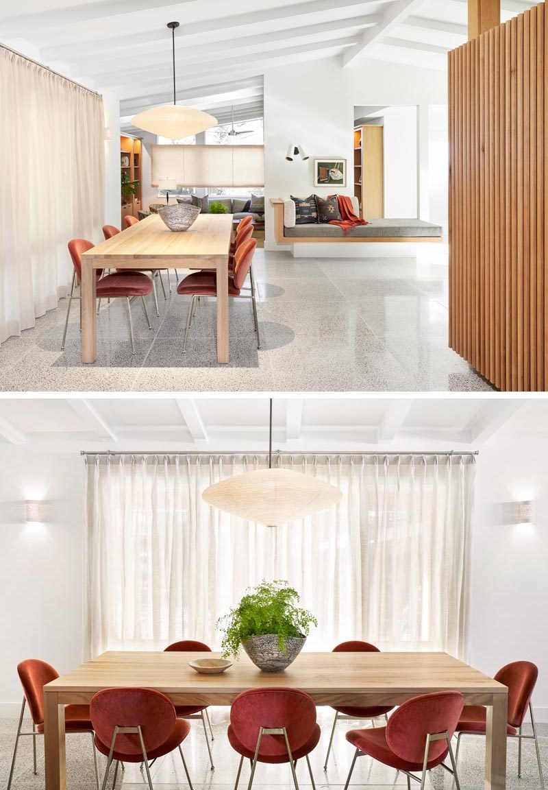 The main social areas of this renovated mid-century ranch house include a dining area with a wood table positioned below a single pendant lamp hanging from the white ceiling. #DiningRoom #DiningArea #PitchedCeiling