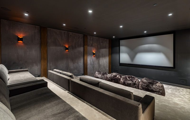 This modern house has a home theater that's been furnished with grey stadium seating and bean bags. #HomeTheater #StadiumSeating