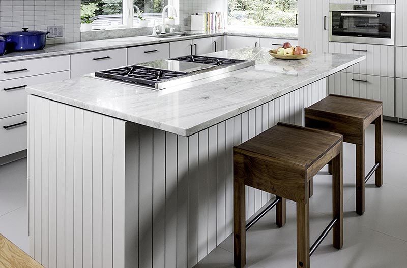 This modern kitchen island provides a place for the cooktop. The overhanging counter not only allows for more counter space, but also creates a home for a couple of stools. #KitchenIsland #KitchenDesign #ModernKitchen