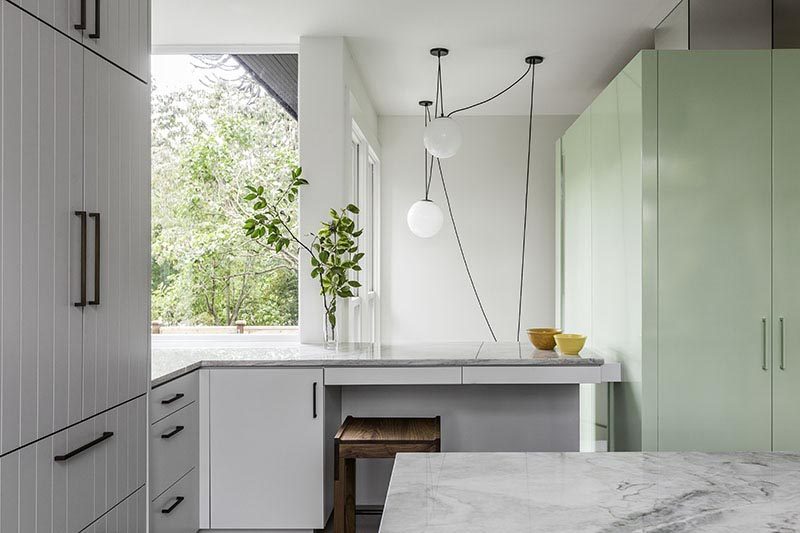 This modern grey kitchen has a small desk area that wraps around the corner and overlooks the stairwell below. #Kitchen #ModernKitchen #Desk