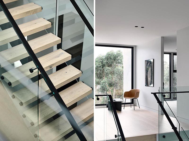 A glass and timber staircase leads to the bedrooms upstairs, while large black-framed windows complement the handrails. #ModernStairs #ModernStaircase #WoodTreads #BlackHandrail