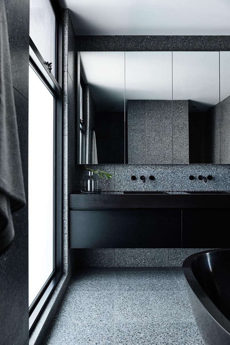 In this modern master bathroom, dark materials like black terrazzo were used to create a luxurious retreat with sense of calm. #MasterBathroom #BlackBathroom #BathroomDesign