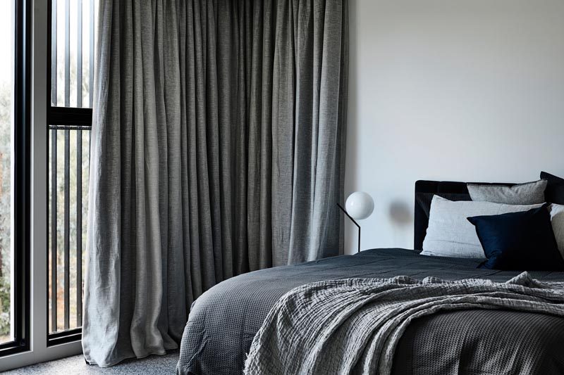 This modern bedroom has soft furnishings and long curtains to create a cozy atmosphere. #ModernBedroom #BedroomDesign