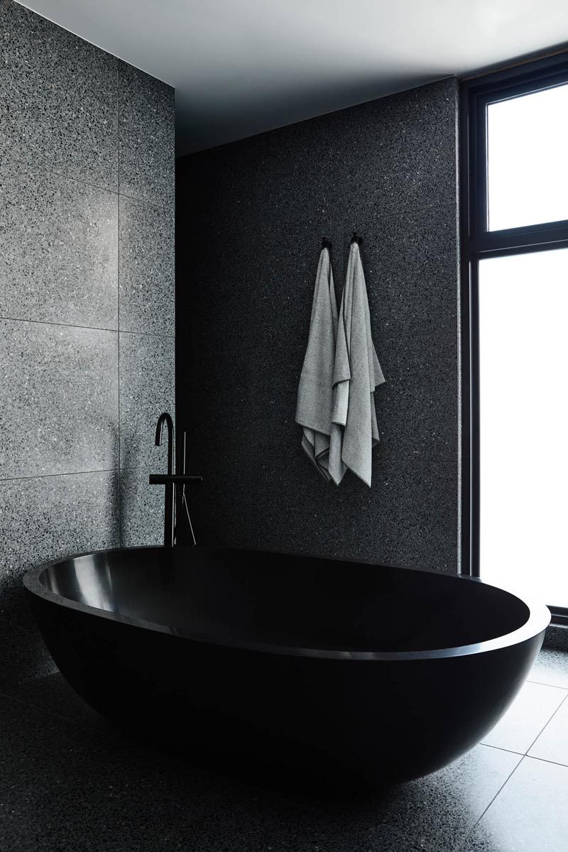 One stand-out feature in this modern master bathroom is the oval-shaped black freestanding bathtub. #BlackBathroom #BlackBathtub #InteriorDesign #ModernBathroom