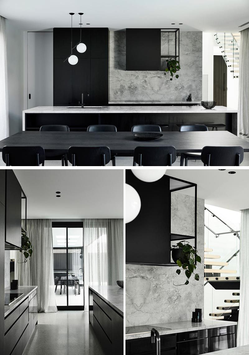 White veined marble lines the kitchen walls and countertops, providing tonal contrast to the black joinery. #ModernKitchen #BlackAndGreyKitchen #KitchenDesign