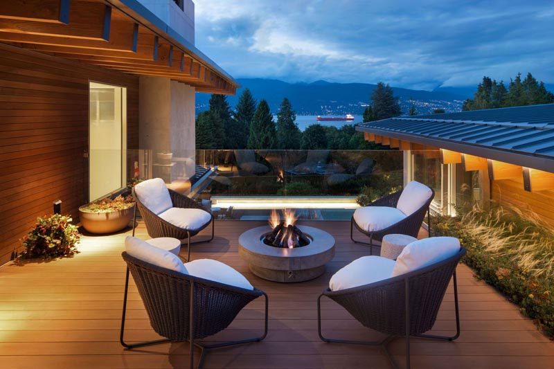 This modern house has an outdoor seating area with a fire bowl, and a glass safety rail allows for unobstructed views. #OutdoorEntertaining #FireBowl