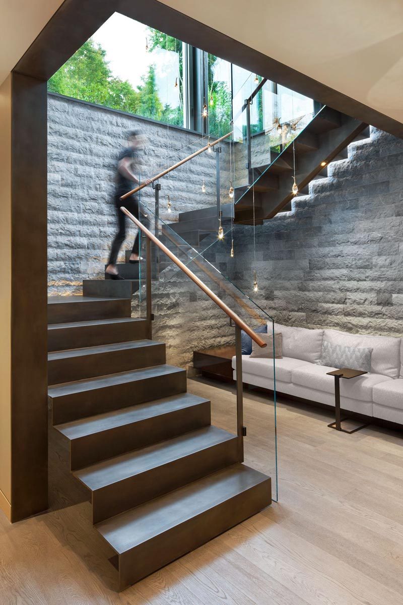 Steel stairs with glass railings lead down to the basement of this modern house. #SteelStairs #Stairs