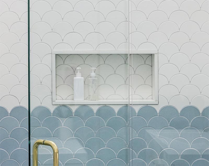 In this modern shower there's a built-in shower niche with a simple white frame that's tiled in the same tile that surrounds it. The shower niche provides a dedicated place to house shampoo bottles and soap, keeping the from gathering on the floor or in a shower caddy. #ShowerNiche #ModernShower #ShowerNicheIdeas