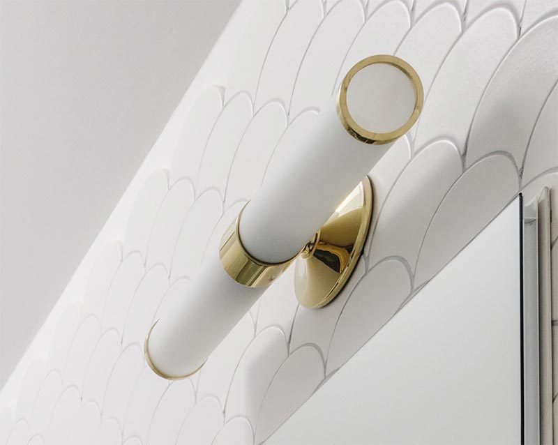 A simple white tube sconce with gold accents is mounted above the mirror, draws the eye upwards, and creates a soft glow for the bathroom. #BathroomLighting #BathroomDesign