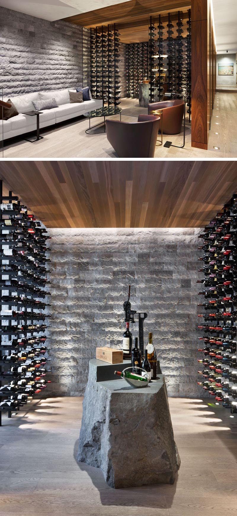 This modern wine cellar has glass walls, plenty of bottle storage, and a stone element that's been designed to be used as a table. #WineCellar #WineRoom #WineStorage