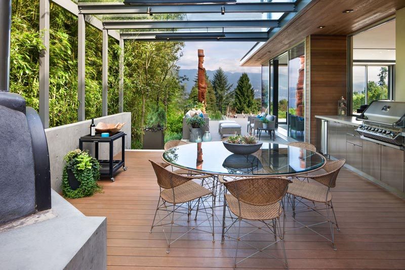 This modern outdoor dining area has a kitchen, wood burning oven, and bbq. #OutdoorDining #BBQ