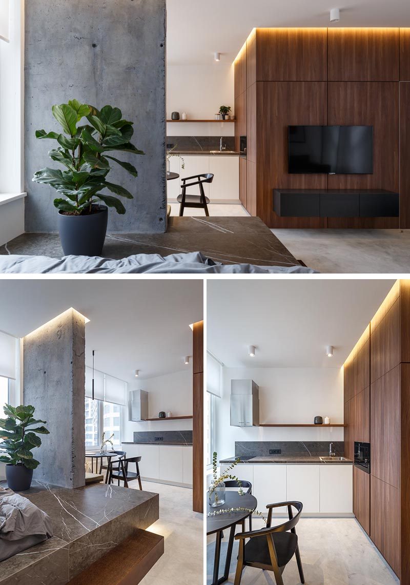 In this small apartment, the wood accent wall in the living room wraps around into the kitchen and dining area. The kitchen features minimalist white cabinets, built-in appliances, a grey countertop, and a simple floating wood shelf. #SmallApartment #WoodAccentWall #SmallKitchen