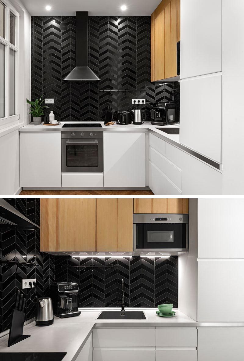 Gloss and matte black tiles have been used to create an accent wall in this modern kitchen, that features minimalist white cabinets and is complemented by the black dining table. #Kitchen #BlackTiles #WhiteCabinets