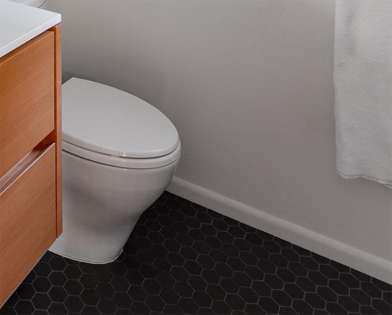 Dark grey hexagonal floor tiles have been used to contrast the wood vanity and white walls in this modern bathroom. #HexagonalFloorTiles #GreyTiles #HexagonalTiles