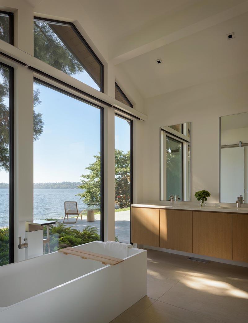 In this modern master bathroom, the main focus is the view of the lake through the floor to ceiling windows that follow the line of the roof. #Windows #ModernBathroom #BathroomDesign