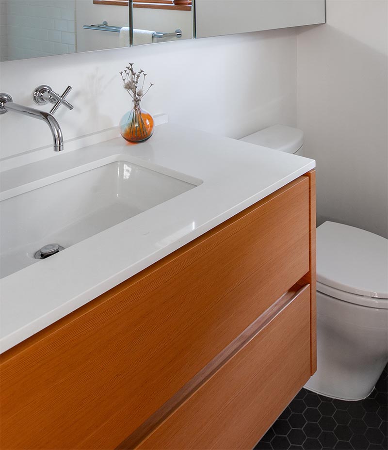 Bathroom Remodel -The dated cream colored vanity with matching tile countertop was replaced by a floating wood vanity with porcelain undermount sink and a 3/4" Caesarstone countertop. #BathroomVanity #BathroomRemodel #ModernBathroom