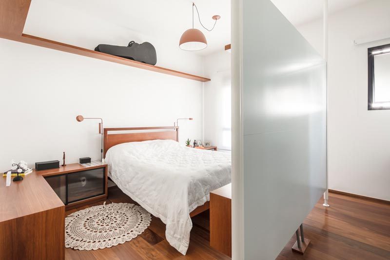 In this bedroom, there's a suspended panel that separates the sleeping area from a wall of closets, and provides a backdrop for low cabinet. #BedroomDesign #ModernBedroom #Partition