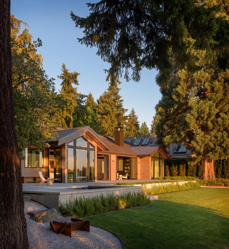 Large operable doors and window walls helped optimize natural light throughout the home and provided views to nearby Lake Washington. The doors open to a deck that steps down to a grassy yard with access to the water. #Architecture #Landscaping #Yard