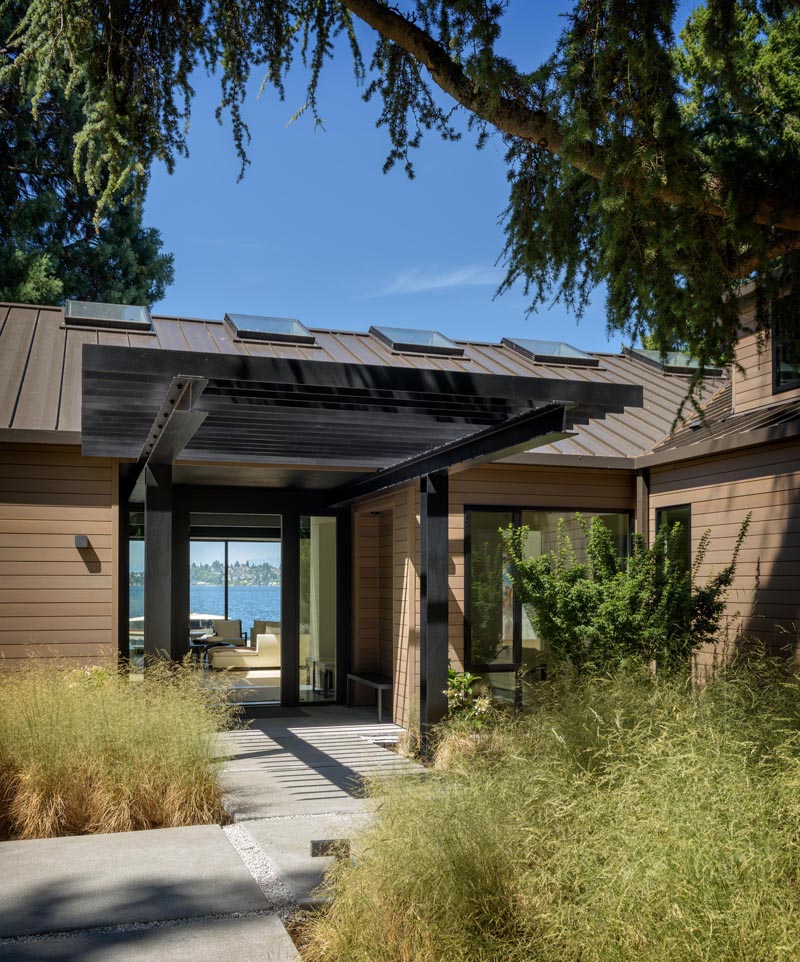 This modern house had a former rustic "lodge style" exterior was updated to a refined language of taut wood planes with a crisp metal roof and windows. #ModernHouse #WoodSiding #Architecture #Entryway #Landscaping