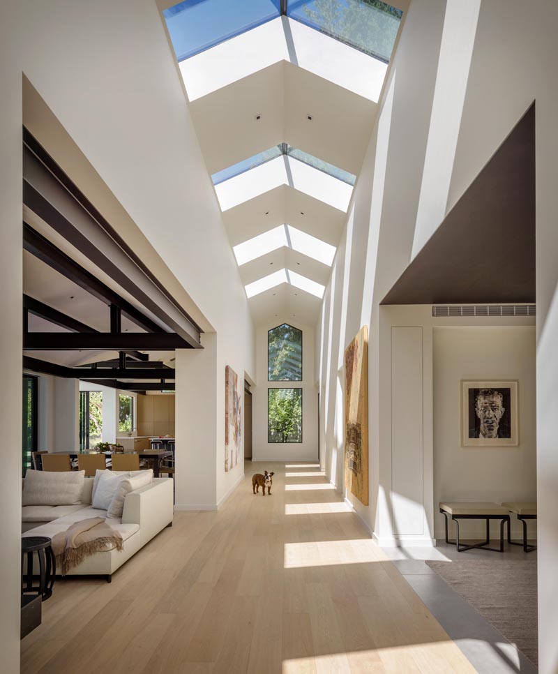 This modern home is organized around a central gallery spine with skylights that draw abundant natural light into the core of the house and surrounding rooms. #Skylights #Hallway #ModernHouse #Architecture