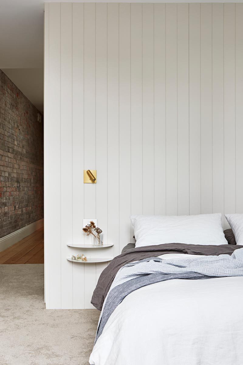 In this modern master bedroom, two simple curved floating shelves are attached to the wall and act as a bedside table. #ModernBedroom #BedroomDesign #MasterBedroom