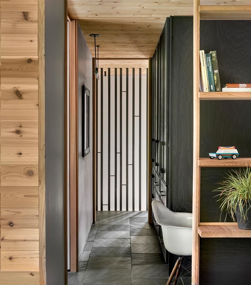 Stairs by the kitchen of this modern house lead up to the second floor owhere the bedrooms are found. Cabinets with a deep green stain provides a closet for the master bedroom. #Storage