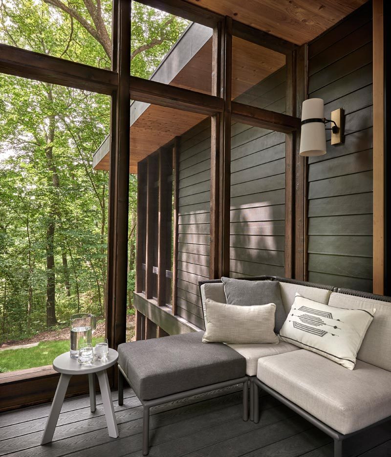 A sunroom off the kitchen of this modern house creates a place to relax in the shade while also enjoying the view of the trees. It also opens to a patio that leads down to the garden. #Sunroom