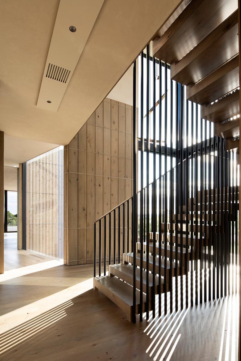 Wood and steel stairs connect the main level of this home to the upper level. The stair handrails play with the light and cast diagonal shadows to the space. #ModernStairs #SteelHandrail #StairDesign