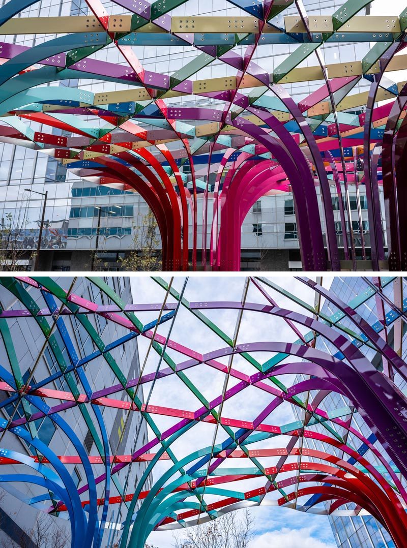 This modern public art installation invites visitors to walk through a grove of archways that have been woven together from intersecting bands of powder-coated aluminum in 28 colors. #PublicArt #PublicInstallation #PublicSculpture #ModernArt #ModernSculpture #Design