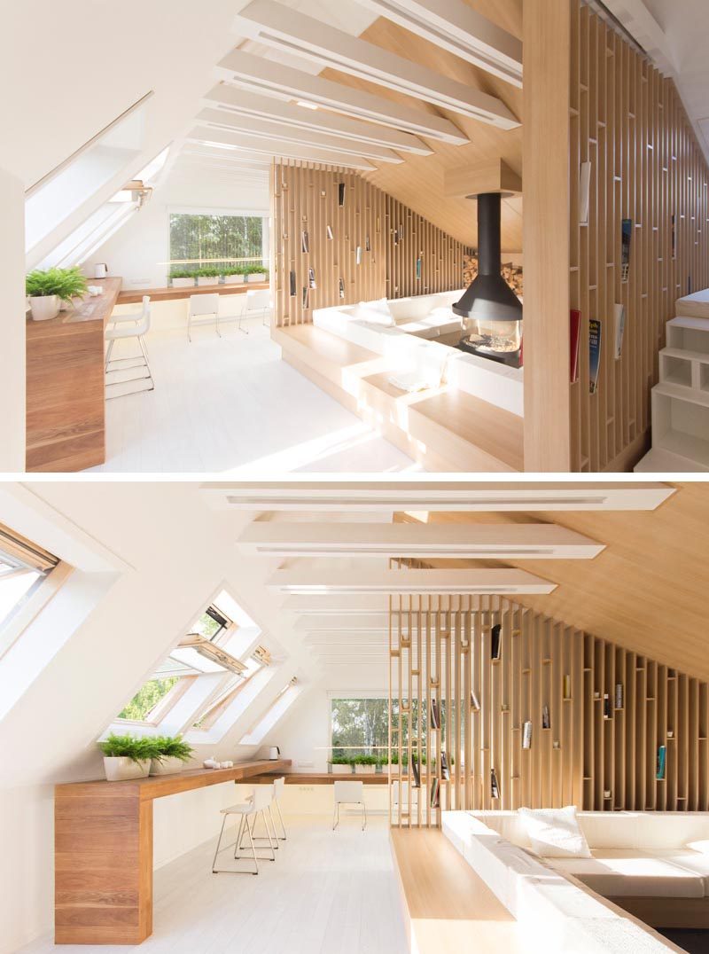 This modern attic has a lounge that wraps around a fireplace, and open wood shelving and ceiling joists with LED lighting. #Lounge #Fireplace #LivingRoom #Shelving #InteriorDesign