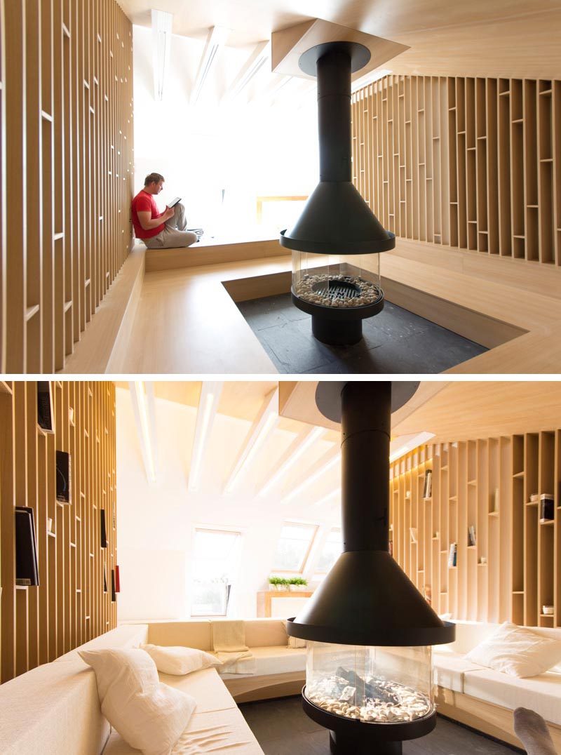 This modern attic has a lounge that wraps around a fireplace, and open wood shelving and ceiling joists with LED lighting. #Lounge #Fireplace #LivingRoom #Shelving #InteriorDesign