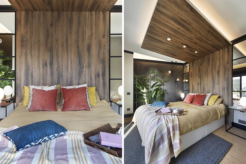 This modern bedroom has a wood headboard that wraps from the wall up onto the ceiling, and acts as an open wood canopy adding a natural touch to the room and defining an area for the bed. It also has hidden lighting that creates a soft glow and highlights the design element. #WoodHeadboard #WrapAroundHeadboard #ModernBedroom #BedroomDesign