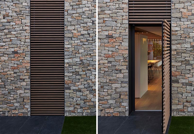 This modern house has a wood slat detail that not only provides visual interest on the facade, but it also hides a door that opens to the interior of the house. #WoodSlat #Facade #ModernHouse #StoneHouse #WoodAccent #Architecture #Doors