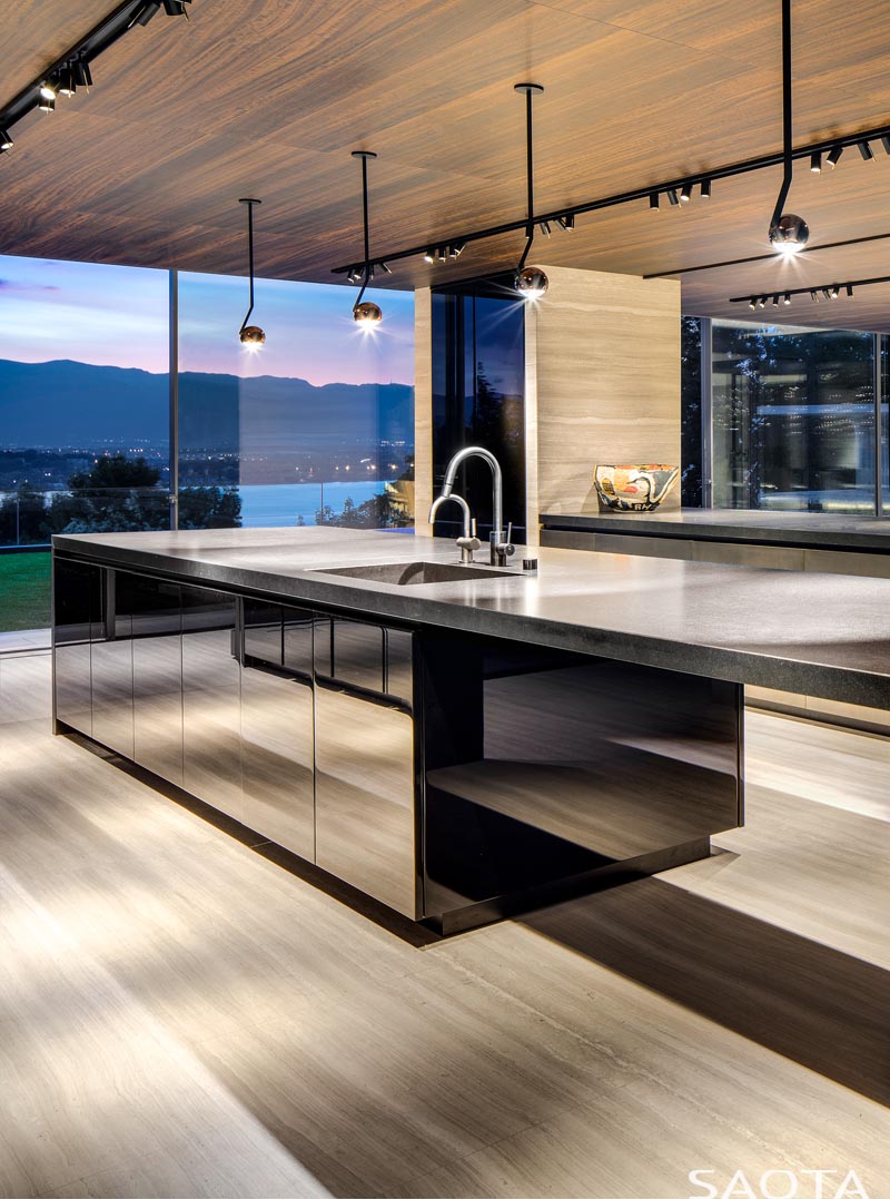 The wood ceiling in this modern kitchen adds warmth, while the kitchen island cabinetry has a mirrored finish. #KitchenDesign #MirroredCabinets