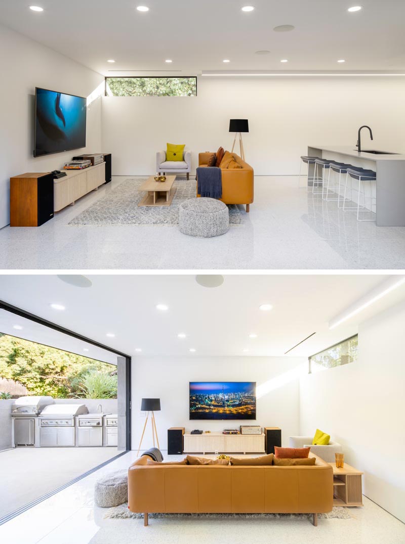 This modern house has a casual open plan living room and kitchen with large sliding glass doors that open to an outdoor bbq area. #Basement #LivingRoom #BBQArea