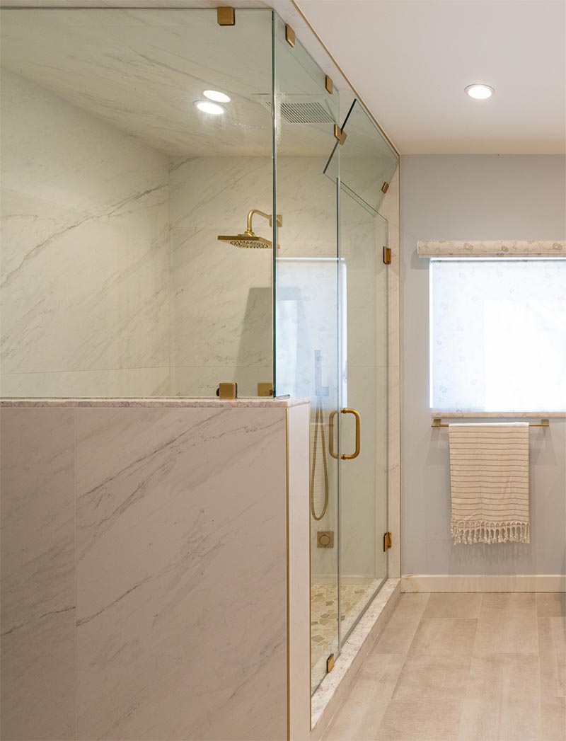 Brass accents have been used throughout this modern bathroom, like in the shower head and the clips that hold the glass in place. #Bathroom #ShowerDesign #EnclosedShower