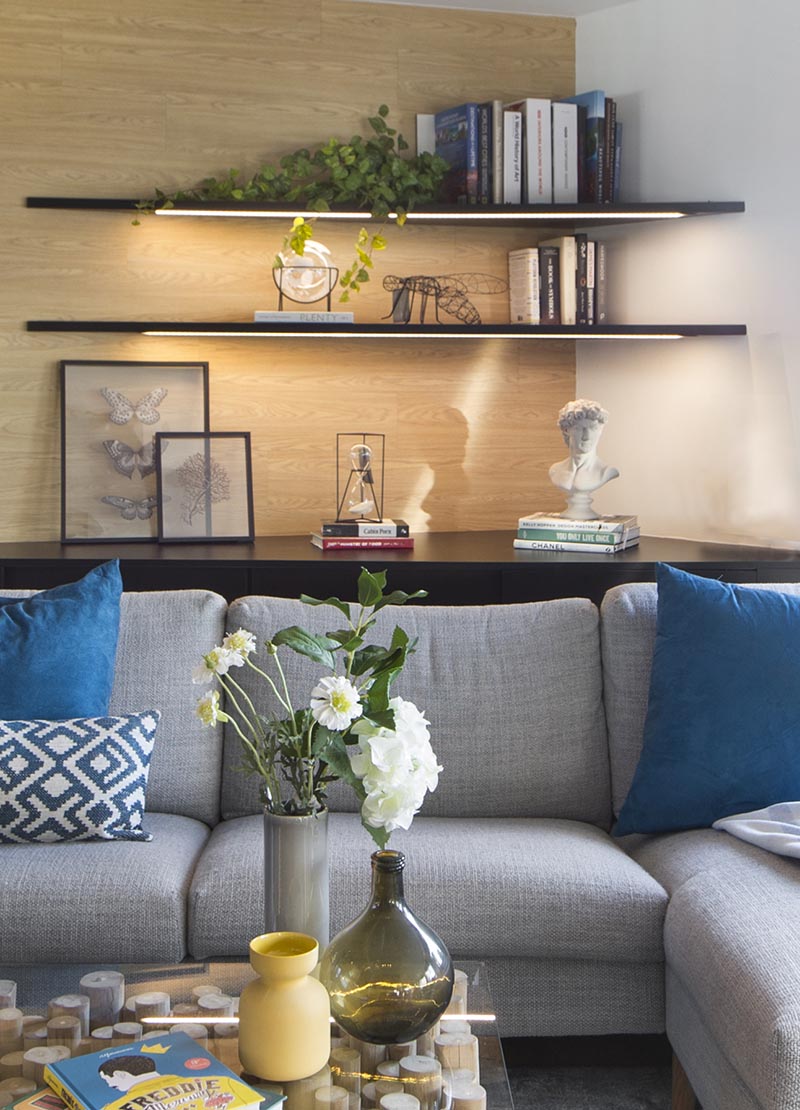 In this modern living room, the corner has been adorned with a pair of shelves that keeps the corner bright and highlights the displayed items. #CornerShelves #CornerShelf #Lighting #ModernLivingRoom